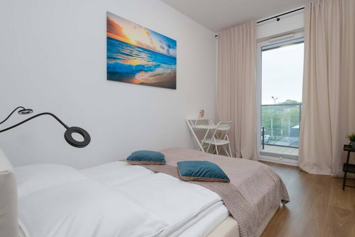 Een groot raam en neutrale tinten in de slaapkamer zorgen voor een lichte en rustgevende ruimte.