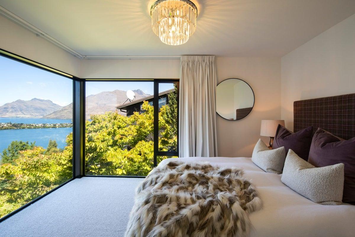 Despiértate rodeado de belleza natural: este dormitorio sereno cuenta con ventanas panorámicas que enmarcan el lago y las vistas de la montaña.