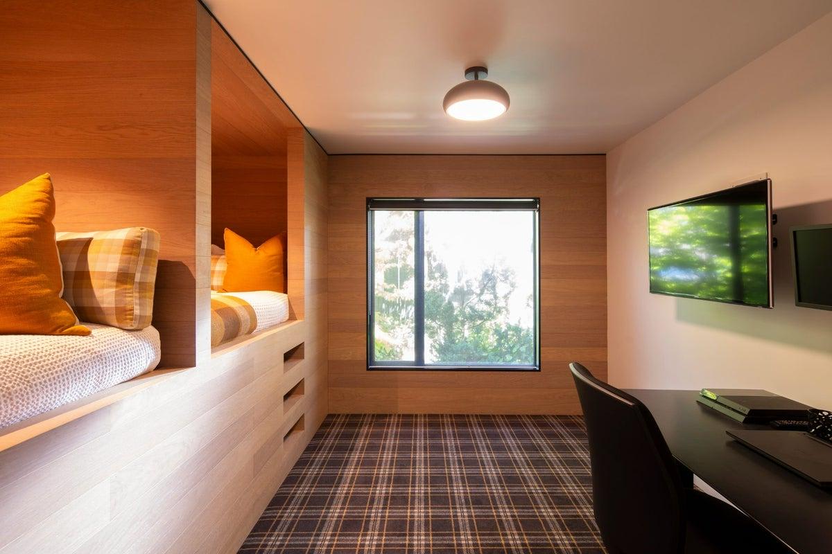 Un espacio divertido y acogedor para niños o adolescentes, con literas de madera personalizadas y un área de juegos/TV.