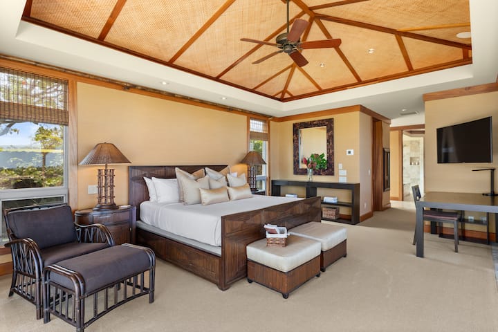 Los techos abovedados, los ricos tonos de madera y la ropa de cama de estilo resort hacen de esta suite principal un refugio sereno.