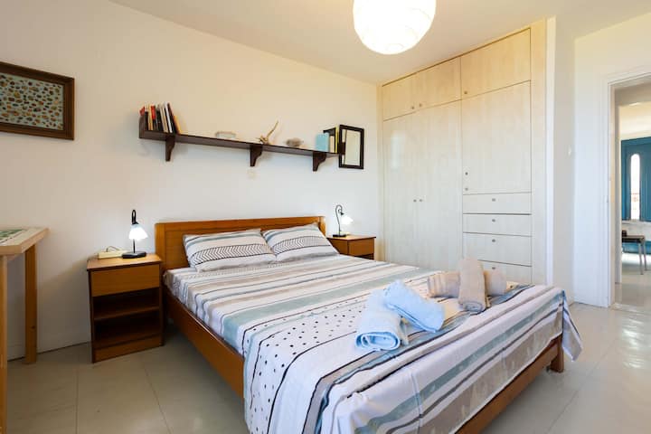 Საძინებელი ორადგილიანი საწოლით – კომფორტული კონფიგურაცია გარდერობითა და ბაღის ხედით.

