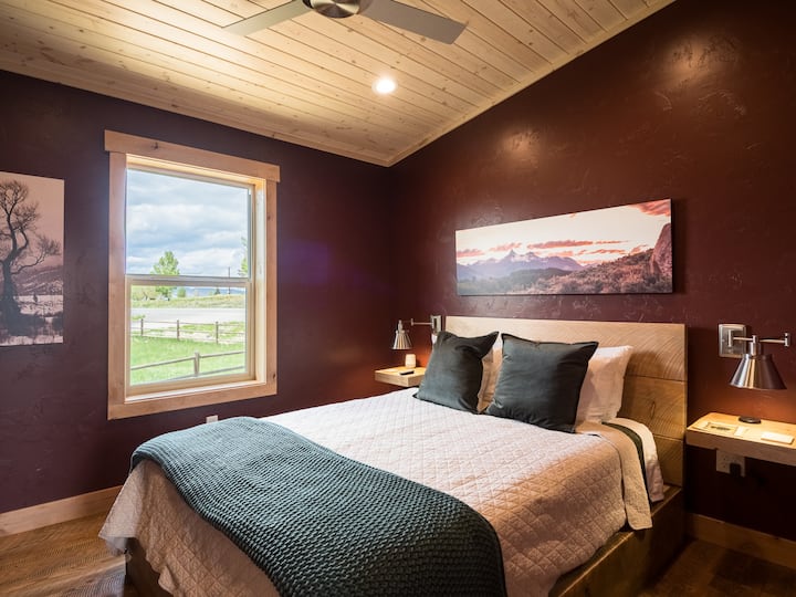 Соба направена за тишина
Завиткана во богати сливи и врамена со топло дрво, оваа брачна спална соба нуди мирно прибежиште со поглед на планината Ратлснејк, црвените задници зад Коди и светлата на градот кои трепкаат кон животот. Тоа е местото каде што зајдисонце