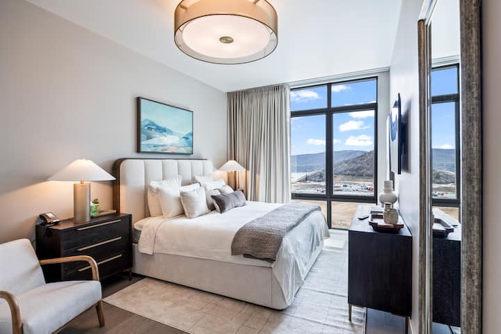 - Bedroom with mountain views through floor to ceiling windows  
- Plush bed with cozy pillows and soft neutral decor design  
- Peaceful space to relax after exploring nearby attractions