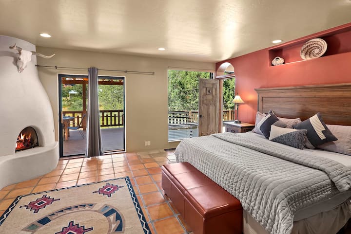 Dormitorio tranquilo con cama tamaño king, chimenea y acceso privado al patio.