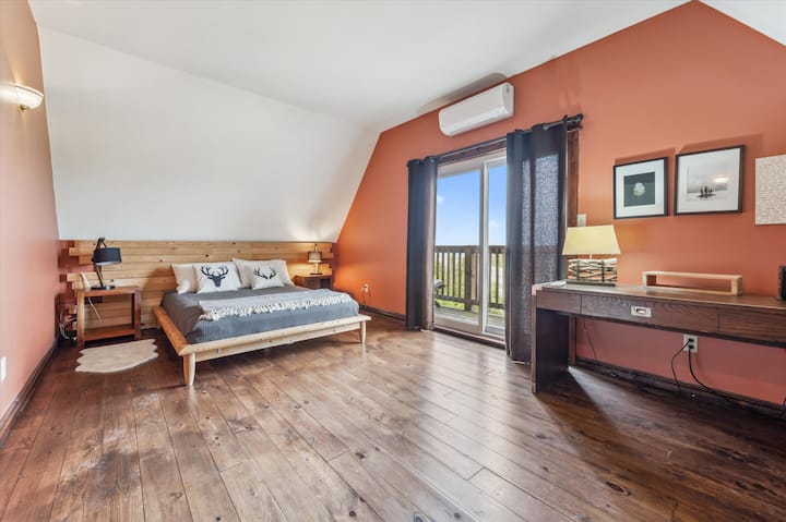 Просторен главен апартман на горно ниво со брачен кревет (широк 150-179 см), ѕид со дрвен акцент и приватен пристап до балконот.