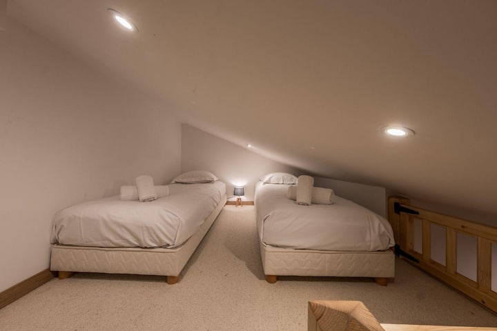 E vendosur nën strehë, kjo papafingo ka dy krevate teke të rehatshme, ideale për adoleshentë ose miq. Ndriçim i ngrohtë, qilima të butë dhe një atmosferë alpine për net të qeta në mal.