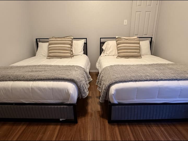 Este espacioso dormitorio cuenta con dos camas de tamaño completo con sábanas de felpa y una decoración sofisticada. Perfecto para familias o grupos que buscan comodidad y diseño refinado.