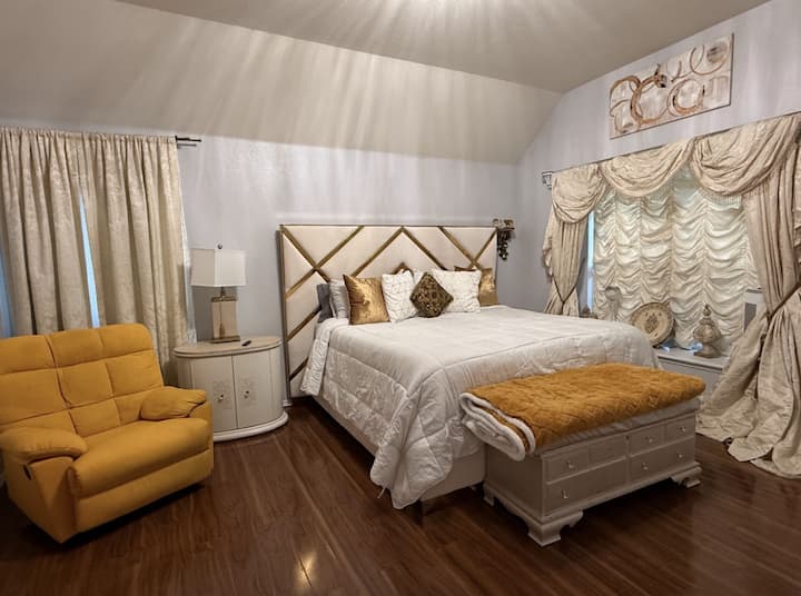 Un dormitorio principal bellamente diseñado con una lujosa cama tamaño king tapizada, sábanas frescas y tonos de colores cálidos para crear un refugio acogedor para descansar y relajarse.