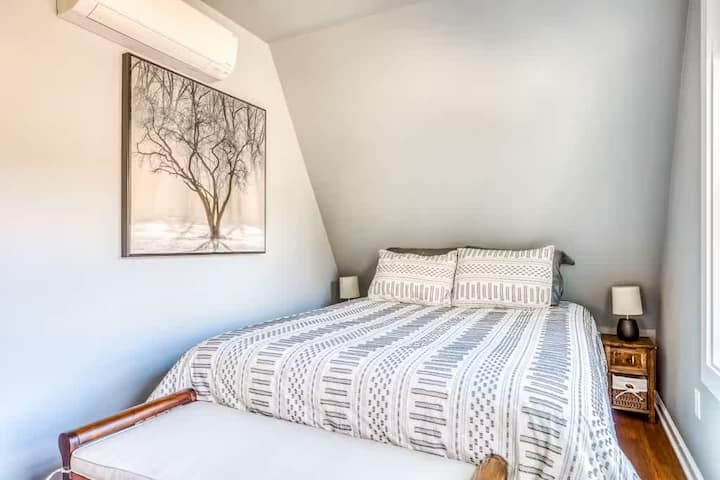 Acogedor y elegante dormitorio con techos inclinados, cama cómoda, decoración moderna y pisos de madera. Tu refugio tranquilo para descansar y relajarte.
