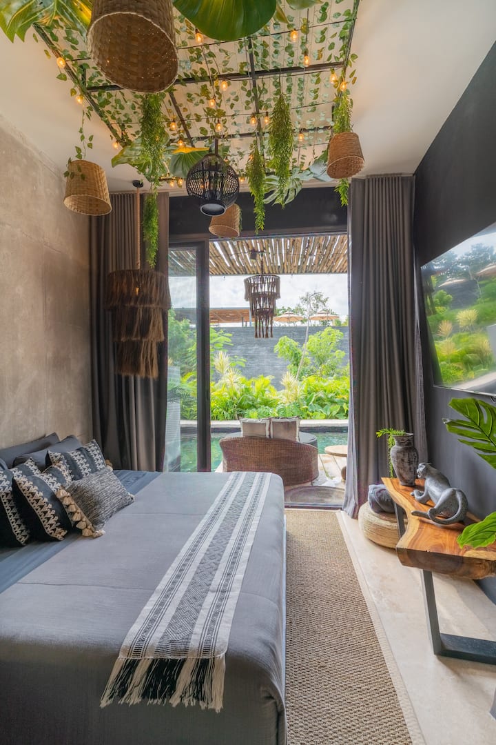 Despiértate con exuberantes vistas tropicales y disfruta de una vida interior y exterior sin interrupciones desde este dormitorio de hermoso diseño con acceso directo a tu refugio privado junto a la piscina.
