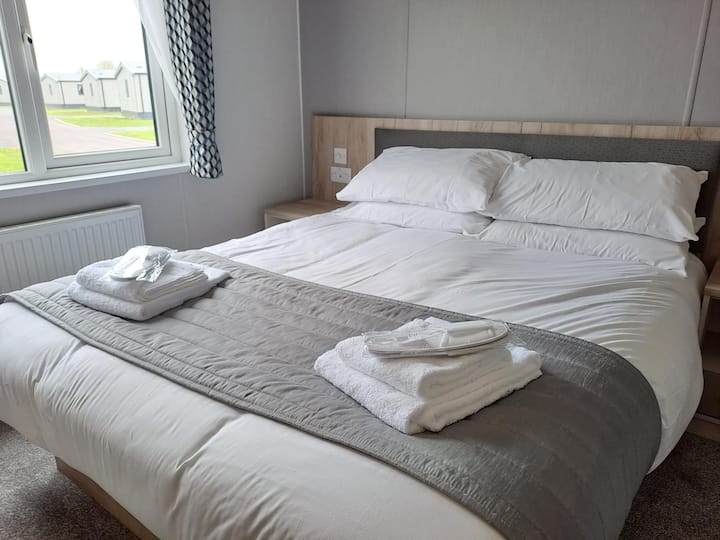 Chambre principale avec lit double luxueux, équipée de linge de lit et de serviettes.
