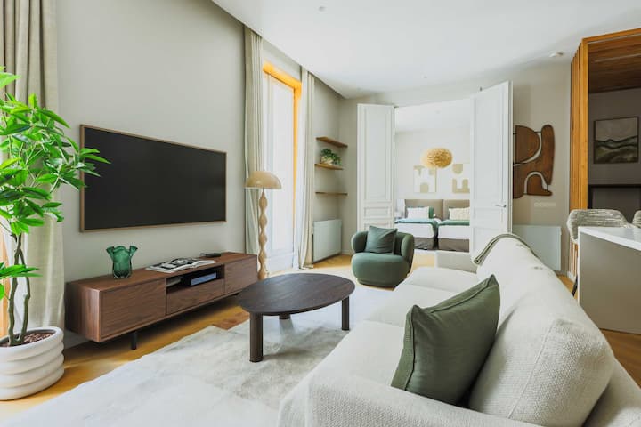 Un salon confortable et lumineux avec canapé et TV écran plat .