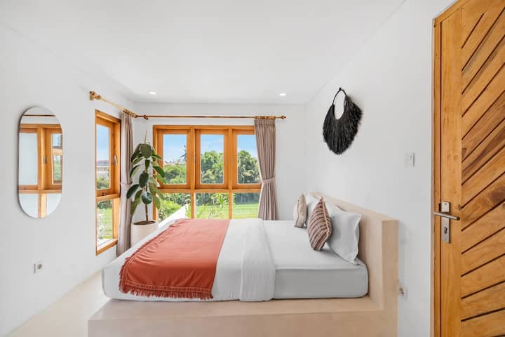 Перниците нудат геометриска шема која го надополнува минималистичкиот стил на собата. Во меѓувреме, големиот прозорец со дрвени рамки е обезбеден за да се внесе осветленост во собата, подобрувајќи го удобниот и пријатен амбиент. 