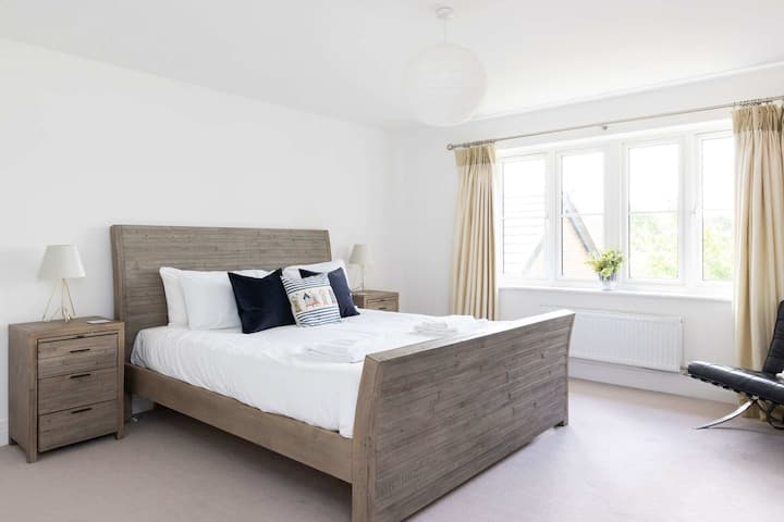 Bienvenido al espacioso dormitorio principal, un refugio luminoso y sereno con una cómoda cama tamaño king y elegantes muebles de madera.