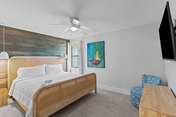 Serene guest bedroom with comfortable bed, accent wall, and flat-screen TV.
