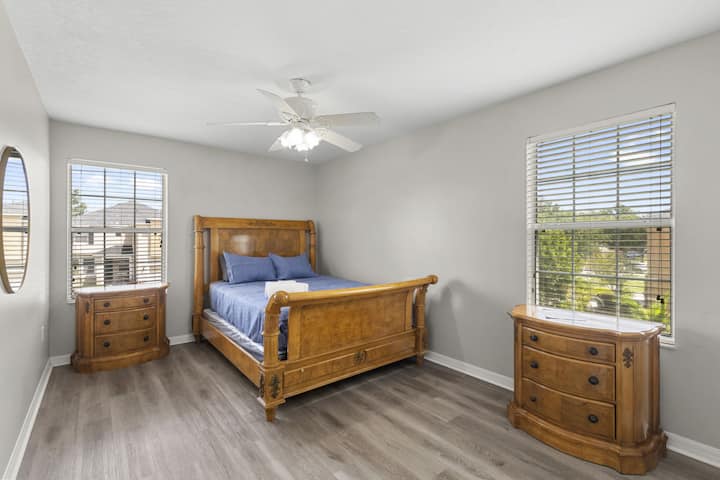 Chambre 3 | Grand lit avec deux tables de nuit et une commode assorties, accentuées par la lumière naturelle provenant de plusieurs fenêtres