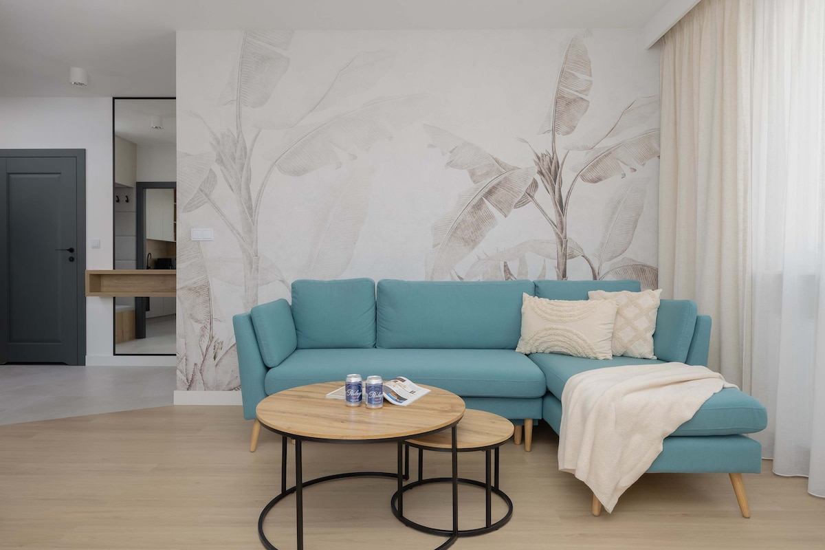 ห้องนั่งเล่นสว่างไสว มีโซฟาสีฟ้าคราม ผนังหินอ่อน และการตกแต่งสไตล์มินิมอลที่ดูหรูหราสมัยใหม่