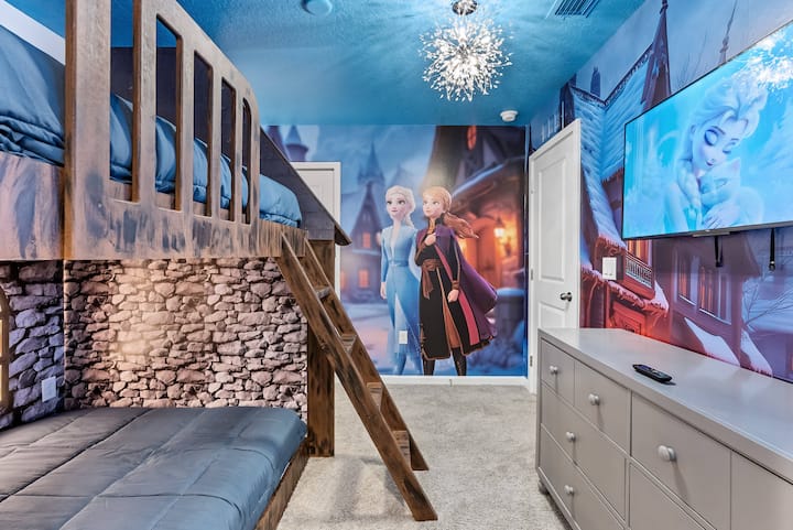 Explore a charming children's bedroom featuring a cozy loft bed crafted from natural wood, a colorful mural of favorite characters, a soft carpet, and a stylish chandelier, creating an ideal playful retreat for your little ones.