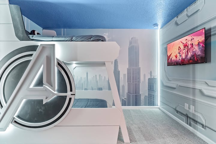 Experience an adventurous bedroom with a striking superhero-themed bunk bed. The sleek furniture and dramatic cityscape mural create a lively atmosphere, perfect for unwinding after a day filled with fun and excitement.