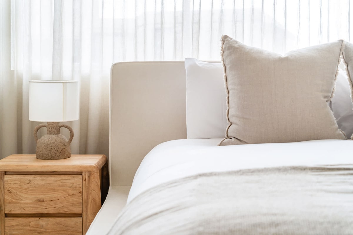 חדר שינה ראשי מעוצב אלגנטית הכולל מיטת קינג סייז מפוארת עם מצעים מפנקים, ארונות מובנים מרווחים ווילונות שקופים שמסביב נוף שקט ועצים. כולל וילונות להחשכת החדר שמבטיחים שנת לילה רגועה