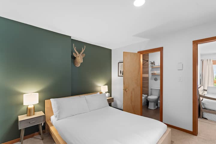 Lower-level guest bedroom with a queen bed, private laundry, and en suite access to the guest bathroom. 