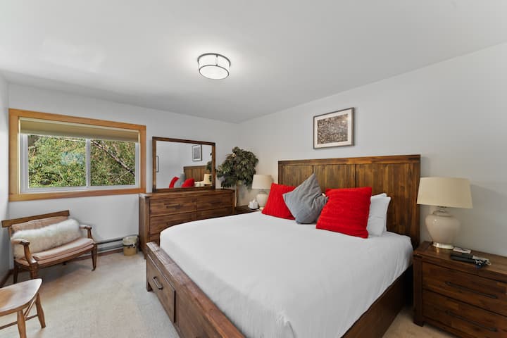 Upstairs primary bedroom featuring a king bed and mounted TV. 