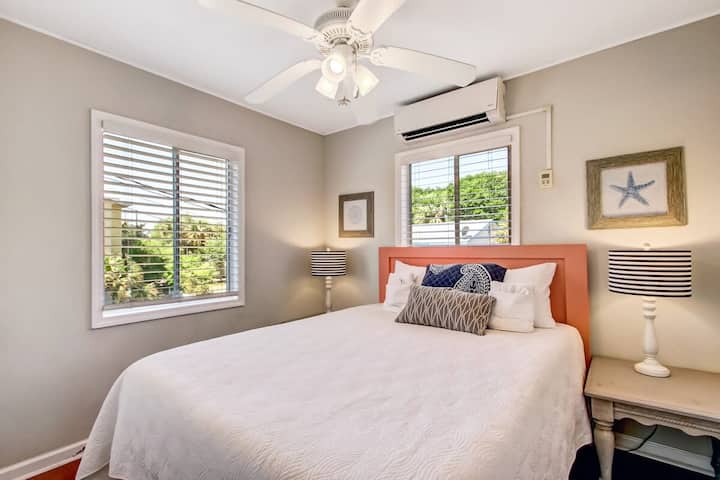 Dormitorio sereno con cabecera de coral y luz natural.