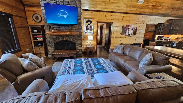 Living area with stone fireplace, wall-mounted smart TV, and leather sectional seating — movie night sorted before dinner's done