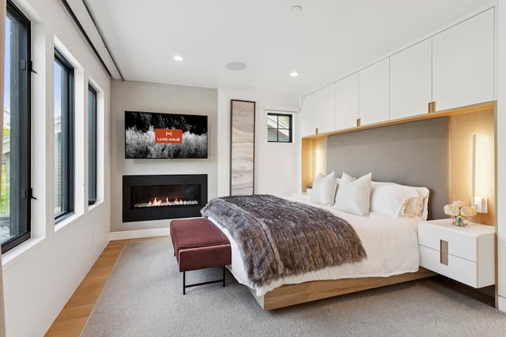 primary bedroom with luxurious bedding and a large fireplace and a flat screen TV with stunning views of the mountains