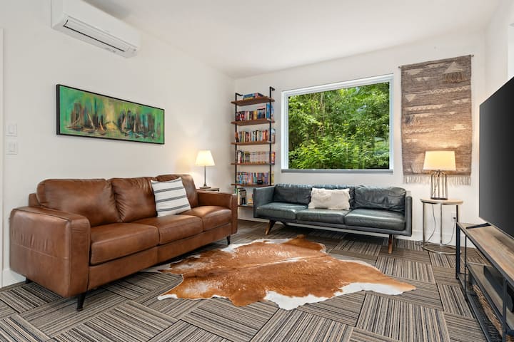 Phòng GALBRAITH tăng gấp đôi như một phòng chờ truyền thông ấm cúng với TV thông minh và ghế sofa ngủ bọc da sang trọng.