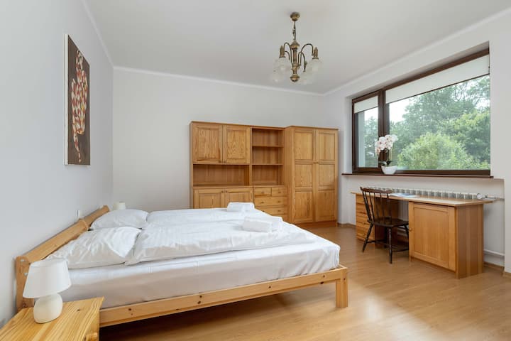 宽敞明亮的卧室，配有木框床、斜天花板和自然光线，非常适合在小木屋式环境中度过安静的夜晚。