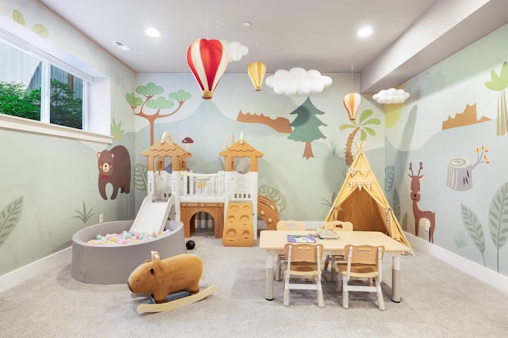 בריכת כדורים ומגלשה מעגנים את המרחב הזה בעיצוב יער, עם אוהל צהוב ושולחן פעילות מלא בספרים. 