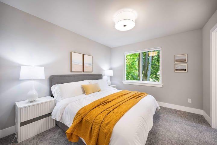 חדר שינה מינימליסטי שבו אפור רך פוגש צהוב שמש - מהשמיכה הקטיפה ועד לכרית הנוי. 