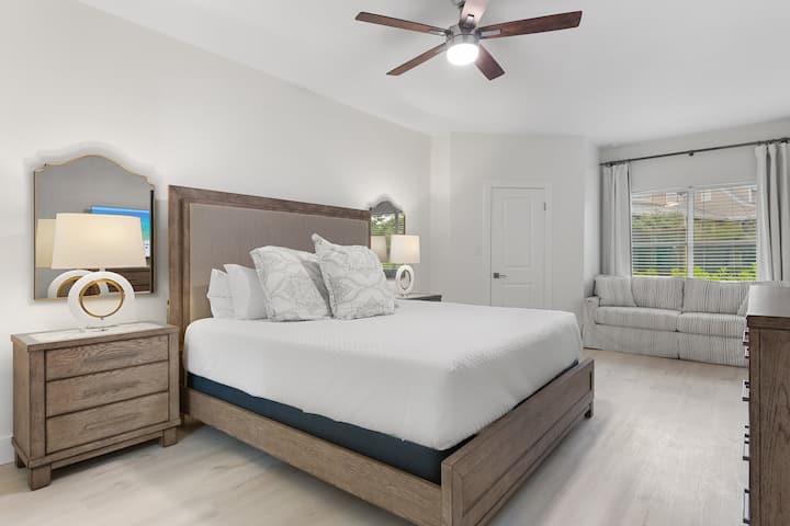 Este dormitorio sereno ofrece una cama tamaño king, un sofá cama tamaño queen, tonos cálidos de madera y una suave elegancia costera.