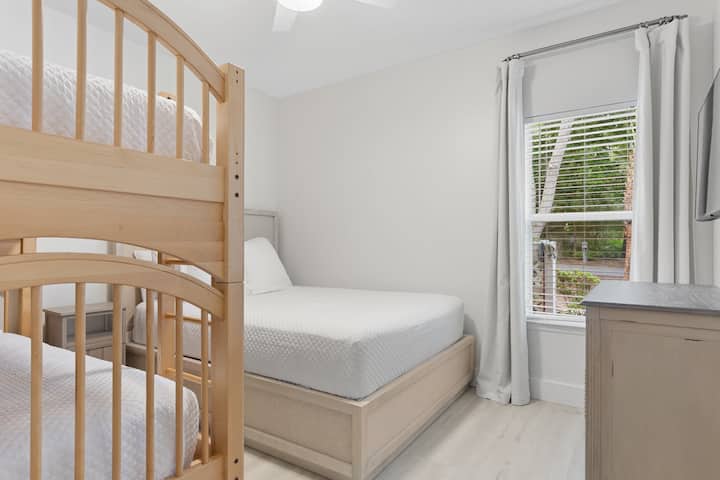 Esta habitación llena de luz ofrece una cama tamaño queen y literas individuales, creando un espacio perfecto para la comodidad familiar.