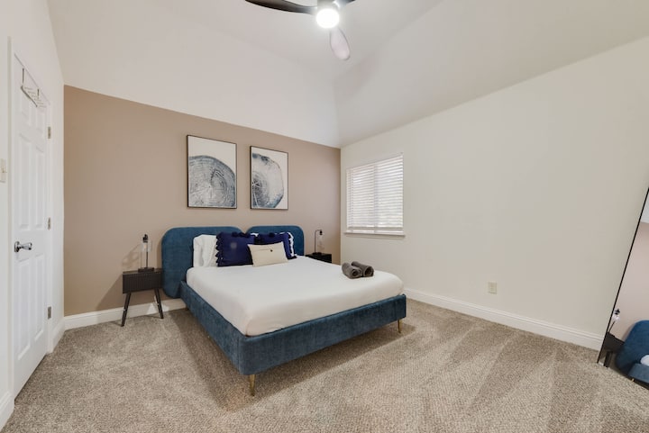 ห้องนอนกว้างขวางพร้อมเตียงสีฟ้าหรูหรา สีโทนสงบ และงานศิลปะบนผนังที่ทันสมัยเพื่อการพักผ่อนที่ผ่อนคลาย