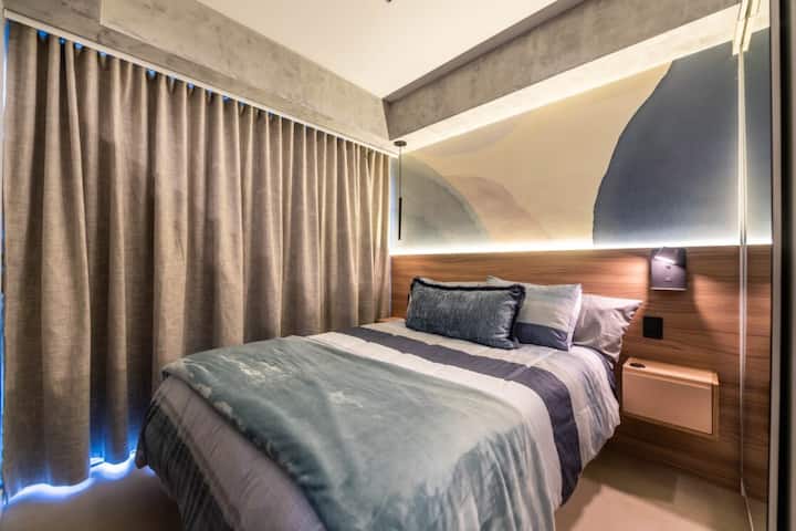 חדר עם מיטה זוגית, מיזוג אוויר והחשכה מושלמת ללילות של שינה. התאורה הרכה, ראש המיטה מעץ והאמנות על הקיר יוצרים אווירה מזמינה ומרגיעה לשהייה שלכם.