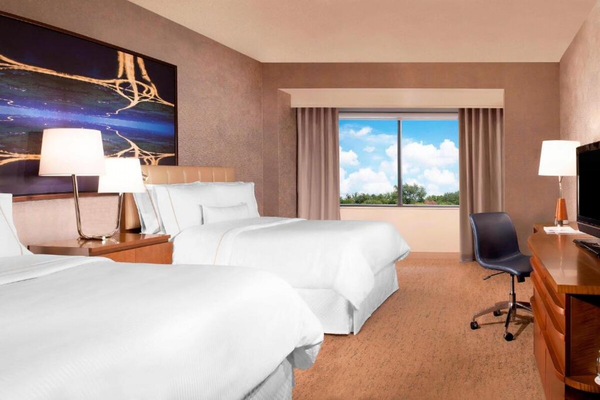 Dhomë me dy krevate me tavolinë pune, dritare të madhe dhe ndriçim të ngrohtë