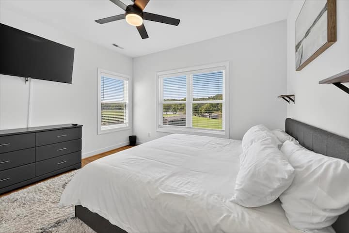 Друга спалня с голямо двойно легло, внимателно проектирана с много естествена светлина, монтиран телевизор и пространство за почивка и възстановяване.