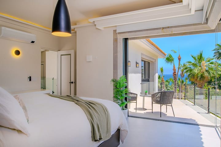 Terras girişi və okean mənzərəsi olan yataq otağı süitası