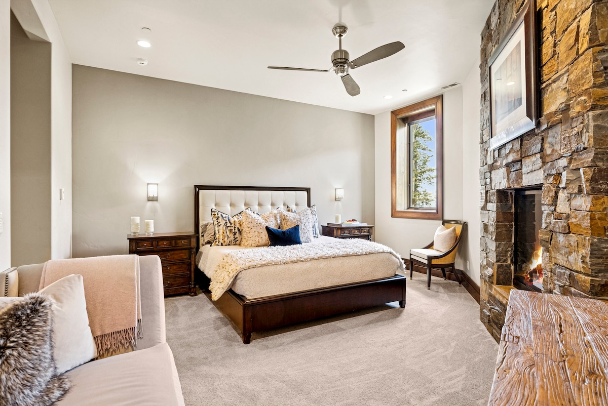 guest suite with luxury bedding and stone fireplace and cozy seating area