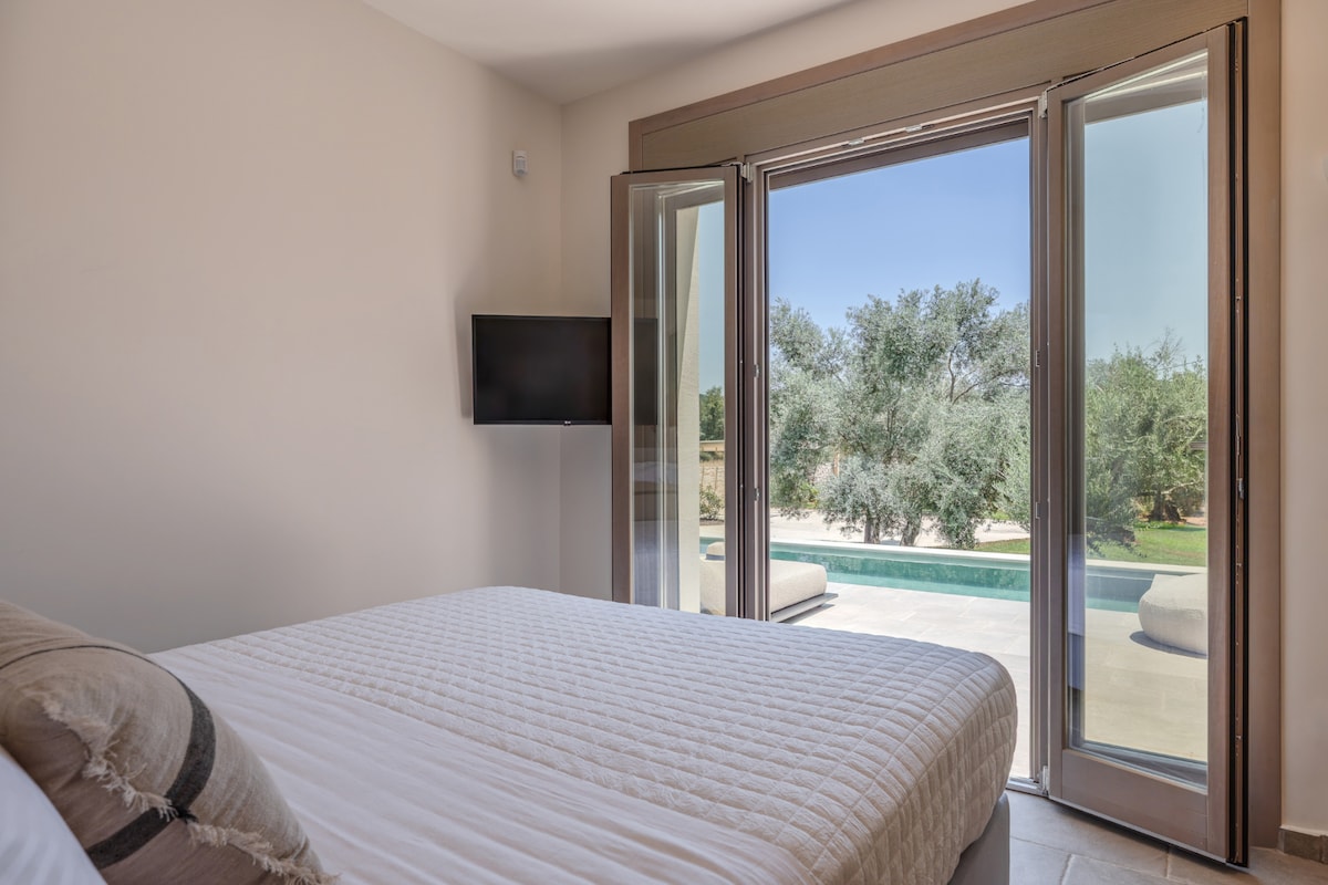 De hoofdslaapkamer met grote openslaande deuren en uitzicht op het zwembad.