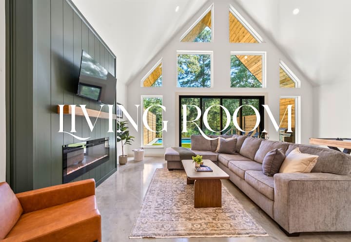 غرفة معيشة واسعة مع مقاعد مريحة وأسقف مرتفعة وجدار مذهل من النوافذ.