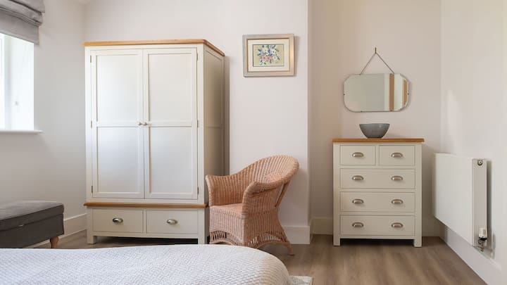 Овој мирен простор има гардероба, фиоки и ноќни масички и стол за читање