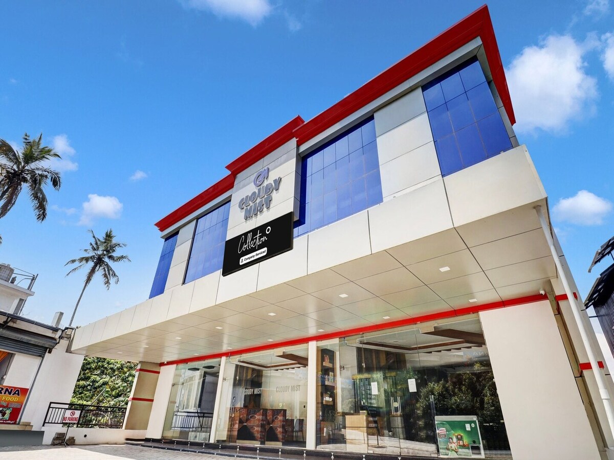 The exterior of the building features a modern design with large glass windows reflecting the sky. A bold sign identifies the property. Palm trees can be seen in the background, contributing to the tropical ambiance of the surroundings.