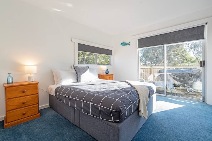 The second bedroom features a queen bed and direct access to the side deck—ideal for a morning stretch in the sea air.