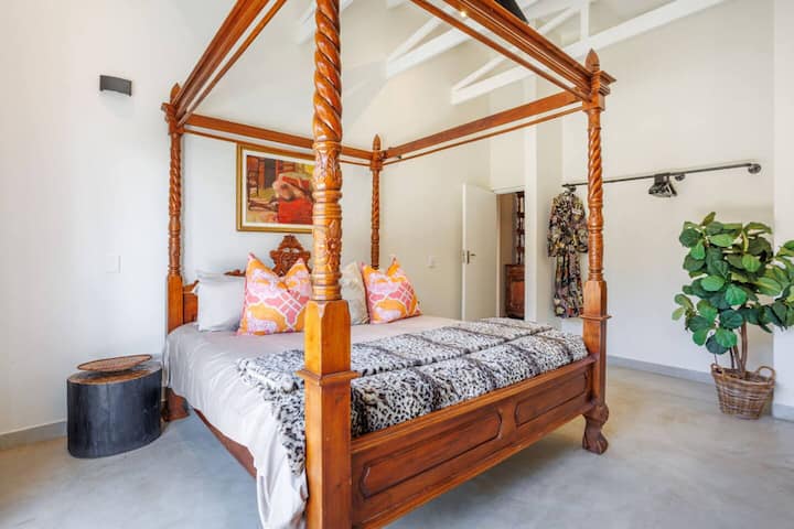 საძინებელი ხის მოჩუქურთმებული საწოლით, ფუფუნების თეთრეულითა და თბილი ტონებით.