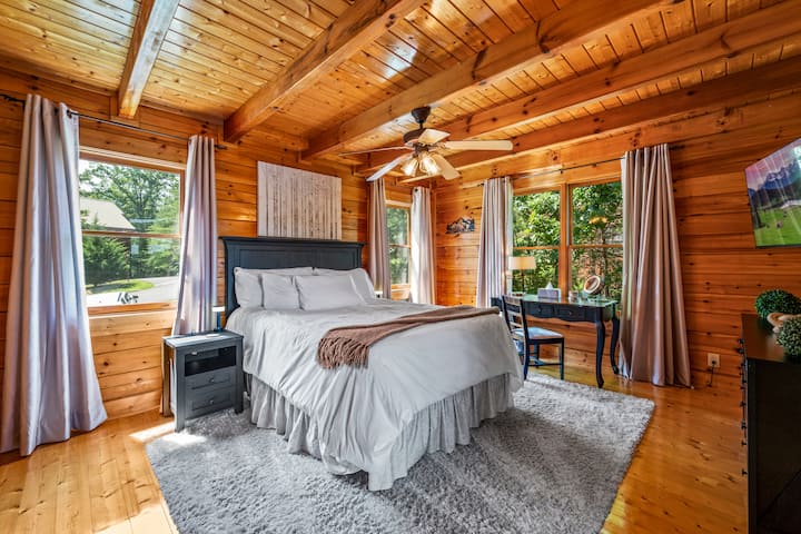 Prostrana glavna spavaća soba s udobnim krevetom, drvenim gredama i toplim prirodnim svjetlom. Okružen prozorima s pogledom na šumu, spoj je rustikalnog šarma i moderne udobnosti za miran odmor u Smoky Mountainsu.
