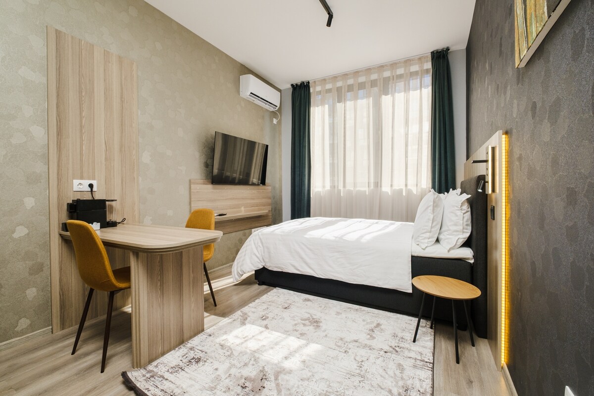 Светла, минималистичка спална соба со удобен кревет и многу светлина. Идеално за парови или самостојни патници кои бараат мирно прибежиште.