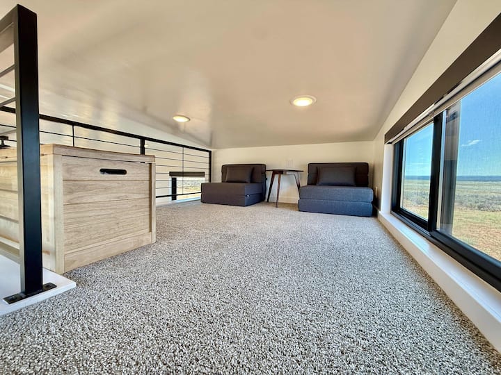 El acogedor loft ofrece espacio adicional y tiene 2 sillas que se pliegan en almohadillas para dormir: relájate con un libro y sumérgete en las vistas panorámicas del desierto a través de grandes ventanas.